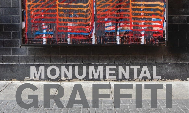 Cropped image of a bookcover. Graffiti on a brick wall in red and white spray painted lines. Text below reads 'Monumental Graffiti'.